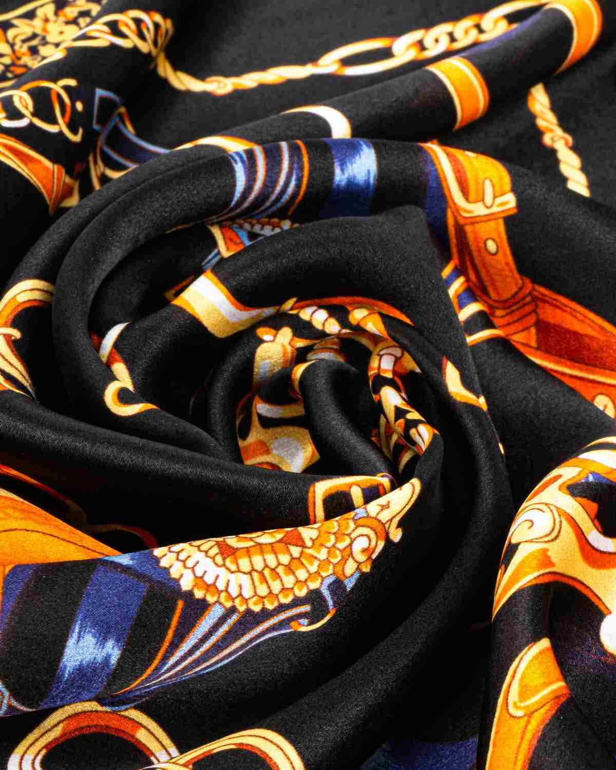 Close-up of a luxurious black and gold silk scarf featuring an elegant chain design.