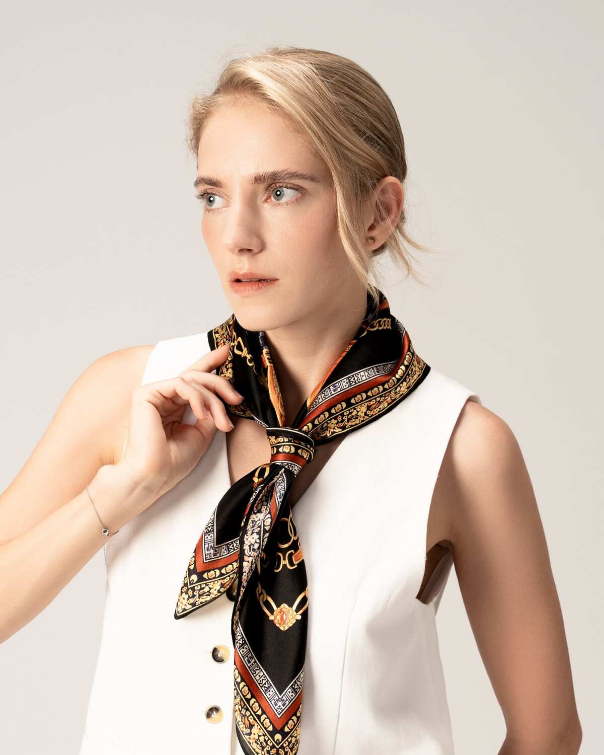 A woman in a white shirt elegantly draped with a black silk scarf, showcasing a sophisticated and stylish appearance.