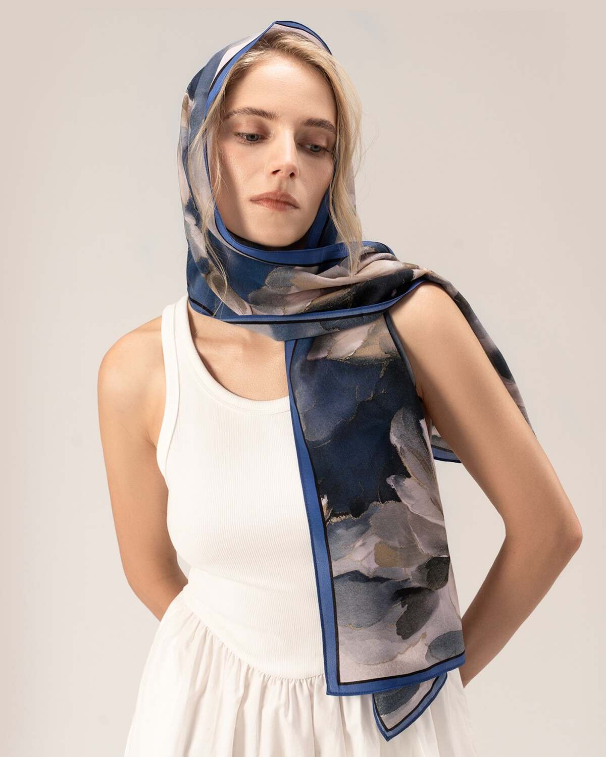 A woman displays a blue and white silk head scarf, adding a touch of elegance to her overall ensemble.