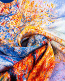 Close-up of a vibrant silk scarf featuring a blue, orange, and yellow design, showcasing intricate patterns and textures.